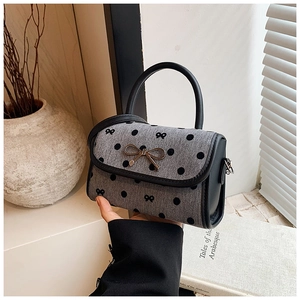 Close-up of gray polka dot fabric mini bag with metal bow buckle and black leather trim
