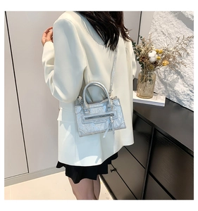 Silver metallic leather crossbody bag with fringe detail shown on shoulder of a model
