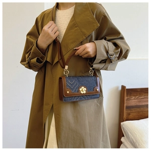 Detail van vintage vierkante crossbodytas met gouden golfpatronen en bruine leren rand