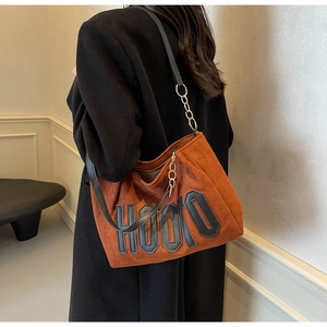 Detail of caramel suede tote bag featuring black HOOLO letter applique and gold chain strap