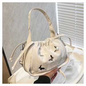 Detail of cream drawstring bag featuring metallic butterfly accents and pleated design