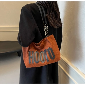 Close-up of brown suede tote bag with HOOTO letter patch and black leather chain strap