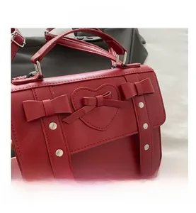 Detalle del bolso rojo de cuero sintético con lazos decorativos y remaches plateados