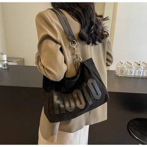 Detail of black large tote bag with embossed HOOTO text and golden chain strap