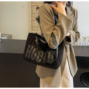 Close-up of black tote bag with HOOTD letter patch and golden metal chain detail