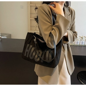 Close-up of black tote bag featuring metallic chain strap and HOOTO letter patch