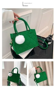 Detailansicht einer grünen gesteppten Filztasche mit Pompon und langem Schultergurt