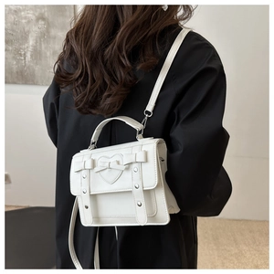 Primer plano del bolso bandolera de cuero blanco con parche de corazón y lazo