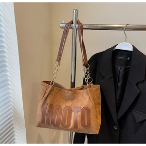 Close-up of caramel suede tote bag featuring HOOTO embroidery and gold chain handle