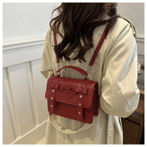 Detalle de mochila de cuero rojo con relieve de corazón, lazo y remaches de plata