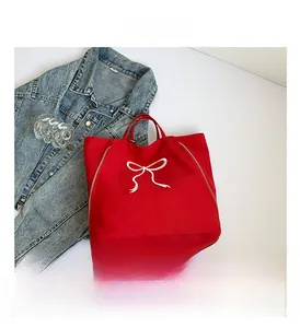 Détail d'un sac à dos en toile rouge avec broderie nœud blanc et fermetures métalliques