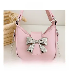 Detailed view of pink mini bag featuring a large silver metal bow and chain strap