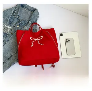 Détail du sac fourre-tout en toile rouge montrant les poignées et le nœud blanc imprimé