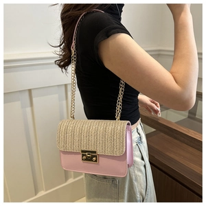 Detail of pink faux leather and straw woven bag with gold chain strap on model