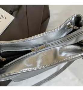 Detail shot of smooth silver metal zipper on metallic wrinkled texture shoulder bag