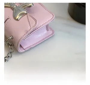 Detail shot of pink crossbody bag showing reinforced stitching and silver bow hardware