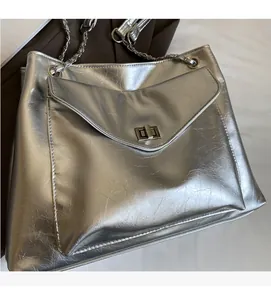 Detail of silver metallic textured crossbody bag with chain strap and metal turn-lock