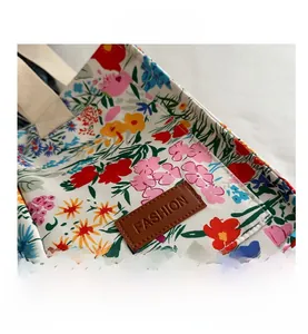 Close-up of colorful floral canvas tote bag featuring an embossed brown leather fashion patch