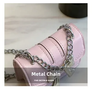 Detail of pink pleated leather bag with silver chunky chain and bow charm