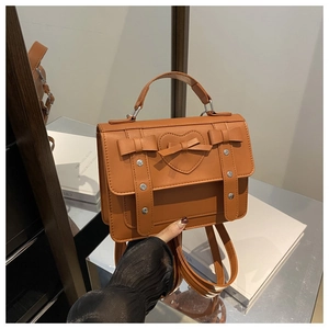 Detalle de bolso de cuero PU marrón caramelo con relieve de corazón, lazo y correas ajustables