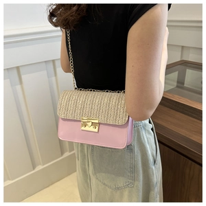 Detail of a pink leather and woven straw crossbody bag with golden chain and lock