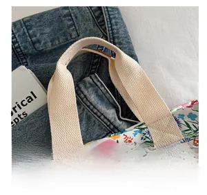 Close-up of durable woven cotton handle on a vibrant floral canvas tote bag