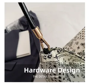 Gros plan du crochet doré et de l'anse en cuir noir sur un sac à main à motif floral