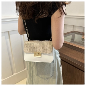Detail of a straw patchwork crossbody bag featuring gold chain strap on a model shoulder