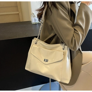 Detail of cream glossy patent leather shoulder bag with silver chain strap and metal lock