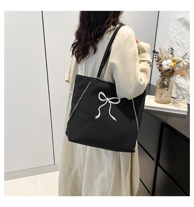 Détail d'un sac cabas en toile noire avec imprimé nœud blanc et fermetures éclair