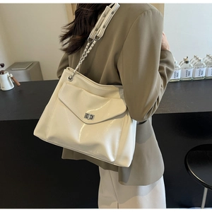 Detail of glossy cream tote bag with silver twist-lock pocket and chain shoulder strap