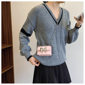 Detail of pink crossbody bag with silver bow ornament and chain strap on model