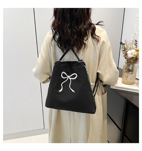 Gros plan du sac à dos en toile noire avec broderie papillon blanche et détail du zip