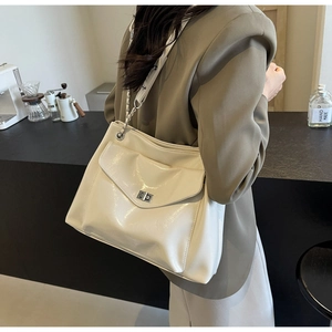 Detail of a creamy white glossy patent leather shoulder bag with a silver twist-lock pocket