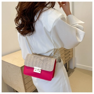 Detail of rose pink straw crossbody bag with gold chain strap on a model shoulder
