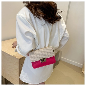 Detail of summer straw crossbody bag with pink faux leather and golden chain strap