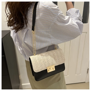 Detail of a chic straw patchwork bag featuring a gold clasp and elegant chain strap