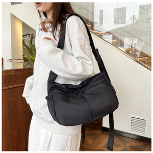 Lifestyle shot of large black nylon crossbody bag with dual zipper pockets and wide strap
