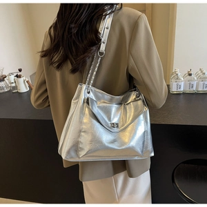 Detailed close-up of metallic silver tote bag with rotary clasp and chain strap detail