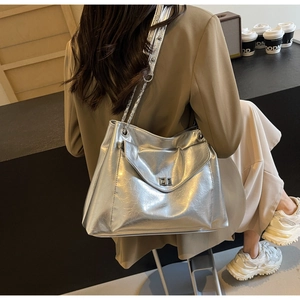 Detail of silver metallic tote bag with twist lock and chain strap on female model