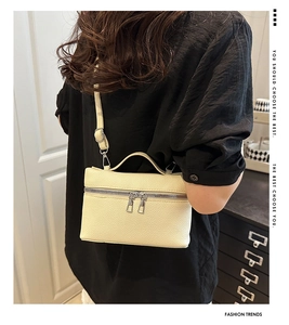 Close-up of cream lychee texture handbag featuring silver double zipper and top handle