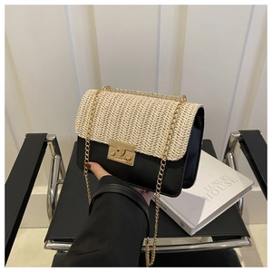 Detail of woven straw and black leather patchwork bag with gold chain and metal clasp