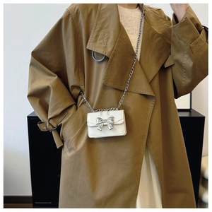 White mini chain crossbody bag with silver bow detail on a stylish khaki trench coat
