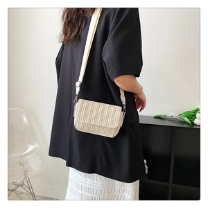 Detail of woven straw crossbody bag with wide strap on model in black blazer