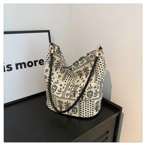 Détail du sac seau en toile avec imprimé floral et bandoulière en cuir noir