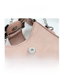 Dettaglio di borsa in pelle rosa con bottone magnetico argento e tracolla a catena