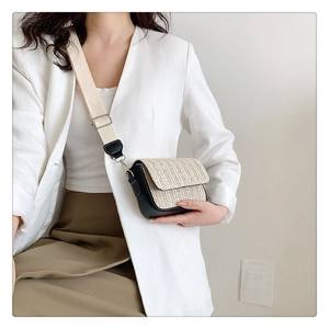 Fashionable woven crossbody bag with leather trim worn with a blazer in a modern setting