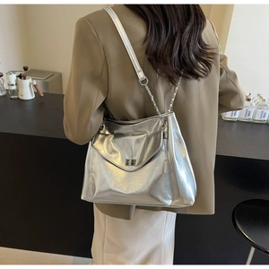 Detail of silver metallic tote bag with chain strap shown on a model in a cafe
