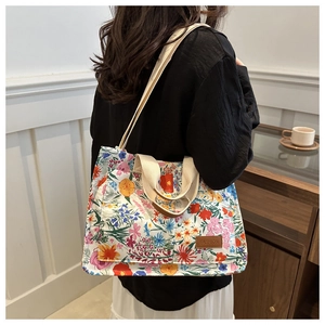 Detail of floral canvas tote bag with dual straps and fashion leather label on front