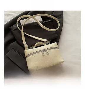 Close-up of beige lychee texture handbag with silver dual zippers on a suit background